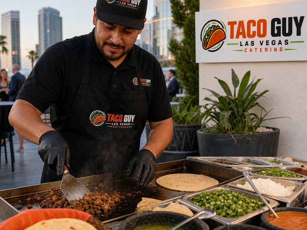 Close view of a taco man catering station with a flat top grill, warm tortillas, chopped onions, cilantro, salsas, and a neatly organized serving line at a Las Vegas venue